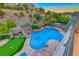 Lush backyard featuring a pool with waterfall, putting green and lounge chairs at sunset at 28 Vista Outlook St, Henderson, NV 89011