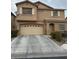 Two-story home featuring tan siding, white shutters, a two-car garage, and well-maintained landscaping at 312 Sierra Breeze Ave, North Las Vegas, NV 89031