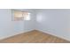 This bedroom is well-lit with wood-look flooring, a window with blinds, and white walls at 3821 1/2 Daisy St # 26, Las Vegas, NV 89119