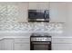Well-lit kitchen features updated gray cabinets, stainless steel microwave, oven and cooktop, and modern tile backsplash at 3821 1/2 Daisy St # 26, Las Vegas, NV 89119