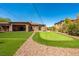 Home's backyard with a putting green, lush grass, and mature landscaping creates a serene outdoor setting at 47 Grand Masters Dr, Las Vegas, NV 89141