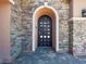 Stylish front door with an arched entryway, multi-colored stone and tiled entryway at 47 Grand Masters Dr, Las Vegas, NV 89141