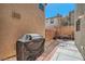 A patio area with a table and chairs sit on a shady side yard next to a covered grill at 517 Primrose Hill Ave, Las Vegas, NV 89178