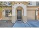 A two-story home with a tan exterior has a covered front door and a two-car garage at 517 Primrose Hill Ave, Las Vegas, NV 89178