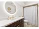 Modern bathroom featuring a vanity with a round mirror, dark cabinets, and luxury gold fixtures at 5604 Ocean Pines Cir, Las Vegas, NV 89130