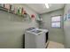 Functional laundry room featuring a washer and dryer, complemented by storage shelves at 6104 Talbot Springs Ct, North Las Vegas, NV 89081