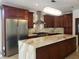 Gourmet kitchen with dark wood cabinetry, stainless steel appliances, marble countertops, and stylish lighting at 7261 Obannon Dr, Las Vegas, NV 89117