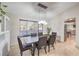 Dining room with a modern chandelier, large window, and sleek table with seating for six guests at 8304 Esmont Ln, Las Vegas, NV 89117