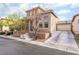 Two-story tan home featuring a 2 car attached garage with a well-maintained lawn and mature trees at 9119 Brilliant Prairie Ct, Las Vegas, NV 89149