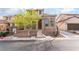Two-story tan home featuring a brick front wall and a well-maintained lawn with mature trees at 9119 Brilliant Prairie Ct, Las Vegas, NV 89149