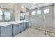Modern bathroom featuring double vanity with gray cabinetry and glass-enclosed shower with multiple showerheads at 9675 Bold Skye Ave, Las Vegas, NV 89166