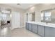Bathroom features a long double vanity with gray cabinets, tiled floors and neutral paint at 9675 Bold Skye Ave, Las Vegas, NV 89166