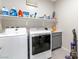 Functional laundry room equipped with a washer, dryer, shelving, and cabinet space at 9675 Bold Skye Ave, Las Vegas, NV 89166