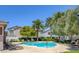 Community pool with lounge chairs, palm trees, and lush landscaping at 10429 Amber Night St, Las Vegas, NV 89183