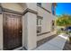 The decorative brown metal front door is surrounded by a beige stucco exterior, complemented by well-maintained landscaping at 1055 Admiral Emblem St, Henderson, NV 89015
