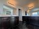 Bathroom featuring dual dark-stained vanities with large mirrors and black tile flooring at 10715 York Manor Ave, Las Vegas, NV 89166