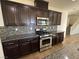 Modern kitchen boasts stainless steel oven and microwave, with granite countertops and dark wood cabinetry at 10715 York Manor Ave, Las Vegas, NV 89166