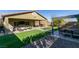 Large backyard with a covered patio, artificial turf, and a pergola-covered seating area with a fire pit at 124 Strone St, Henderson, NV 89012