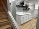 Dining area with white cabinets, quartz countertop, floating shelves, and wood-look floors at 150 Greenbriar Townhouse Way, Las Vegas, NV 89121
