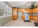 Bright kitchen featuring tiled floors, oak cabinets, granite countertops, and shuttered windows at 213 Red Coral Dr, Henderson, NV 89002