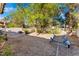 Open backyard with gravel, plants, mature trees and a boat trailer at 3040 Ocean Port Dr, Las Vegas, NV 89117