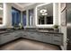 Modern bathroom featuring gray cabinets, stone counters, and a large, illuminated mirror with pendant lighting at 545 Overlook Rim Dr, Henderson, NV 89012