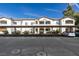 White two-story condo building featuring covered parking and well-maintained landscaping at 5655 E Sahara Ave # 1060, Las Vegas, NV 89142