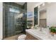 Green tiled shower with glass door, complemented by a sink with quartz countertop and stylish mirror at 5719 Christian Creek Ct, Las Vegas, NV 89149