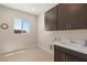 Well-lit laundry room featuring dark wood cabinets, a sink, and a window providing natural light at 5719 Christian Creek Ct, Las Vegas, NV 89149