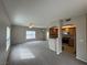 Open-concept living room with neutral carpet, ceiling fan, and passthrough to kitchen at 6160 Rumrill St # 207, Las Vegas, NV 89113