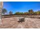 Expansive brick-paved backyard featuring a table with chairs surrounded by a wooden fence and mature trees at 7025 N Eula St, Las Vegas, NV 89149