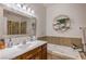 Bright bathroom with a modern sink, vanity, large mirror, and a separate tub with decorative wall accents at 7025 N Eula St, Las Vegas, NV 89149