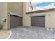 Two-car garages with gray doors, modern building design, and paved driveway at 7457 Onyx Star St, North Las Vegas, NV 89084