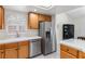 Modern kitchen showcasing stainless steel appliances, wooden cabinets, tile countertops and sink with shuttered window at 9581 Ancala Hollow Ct, Las Vegas, NV 89148