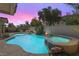 Backyard pool and spa at dusk, with cozy seating, warm lighting and lush landscaping at 9581 Ancala Hollow Ct, Las Vegas, NV 89148