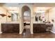 Luxurious primary bathroom with dual vanities, dark wood cabinets, and arched doorway to the bedroom at 1013 Baronet Dr, Las Vegas, NV 89138
