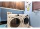 Well-lit laundry room with front-loading washer and dryer, upper cabinets, and blue accent wall at 1013 Baronet Dr, Las Vegas, NV 89138