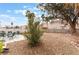 Open backyard featuring gravel, patio, chairs and tropical trees at 1017 Cliffbrook Hedge Ave, North Las Vegas, NV 89081