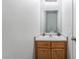 Half-bath featuring a wood cabinet, neutral countertop, large mirror and white walls at 1017 Cliffbrook Hedge Ave, North Las Vegas, NV 89081