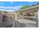 Spacious backyard showcases a covered patio with decorative rock landscaping, stone brick trim, and mature trees at 1326 Winter Solstice Ave, Henderson, NV 89014