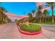Scenic view of the neighborhood entrance with beautiful landscaping, colorful sky, and elegant stone signage at 21 Via Visione # 101, Henderson, NV 89011