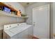 Bright laundry room with a standard washer and dryer, with shelving above for ample storage at 2308 Avery Dr, Las Vegas, NV 89108