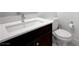 Modern bathroom with white countertop, dark wood vanity and a toilet with paper roll holder at 2685 Conifer Canyon St, Henderson, NV 89044