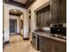 A stylish bar area with custom cabinetry and a built-in wine fridge next to hallway with architectural arches at 30 Meadowhawk Ln, Las Vegas, NV 89135