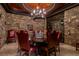 Elegant dining room featuring stone walls, rich wood table, red seating and a decorative chandelier at 30 Meadowhawk Ln, Las Vegas, NV 89135