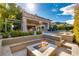 Inviting backyard area with a cozy stone fire pit, lush greenery, built-in seating and a partial view of the home's exterior at 30 Meadowhawk Ln, Las Vegas, NV 89135