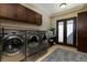 Laundry room with stainless steel machines, dark wood cabinets, and a gray rug on the tile floor at 30 Meadowhawk Ln, Las Vegas, NV 89135