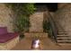 Inviting patio with a stone waterfall feature, fire pit, stone bench with pillows, and staircase to an upper level at 30 Meadowhawk Ln, Las Vegas, NV 89135
