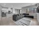 Open-concept living room with modern gray sectional, tile flooring, and an adjacent kitchen area at 3192 Timorasso Ave, Henderson, NV 89044