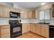 This kitchen features light wood cabinets, black appliances, and wood-look tile flooring at 4678 San Benito St, Las Vegas, NV 89121